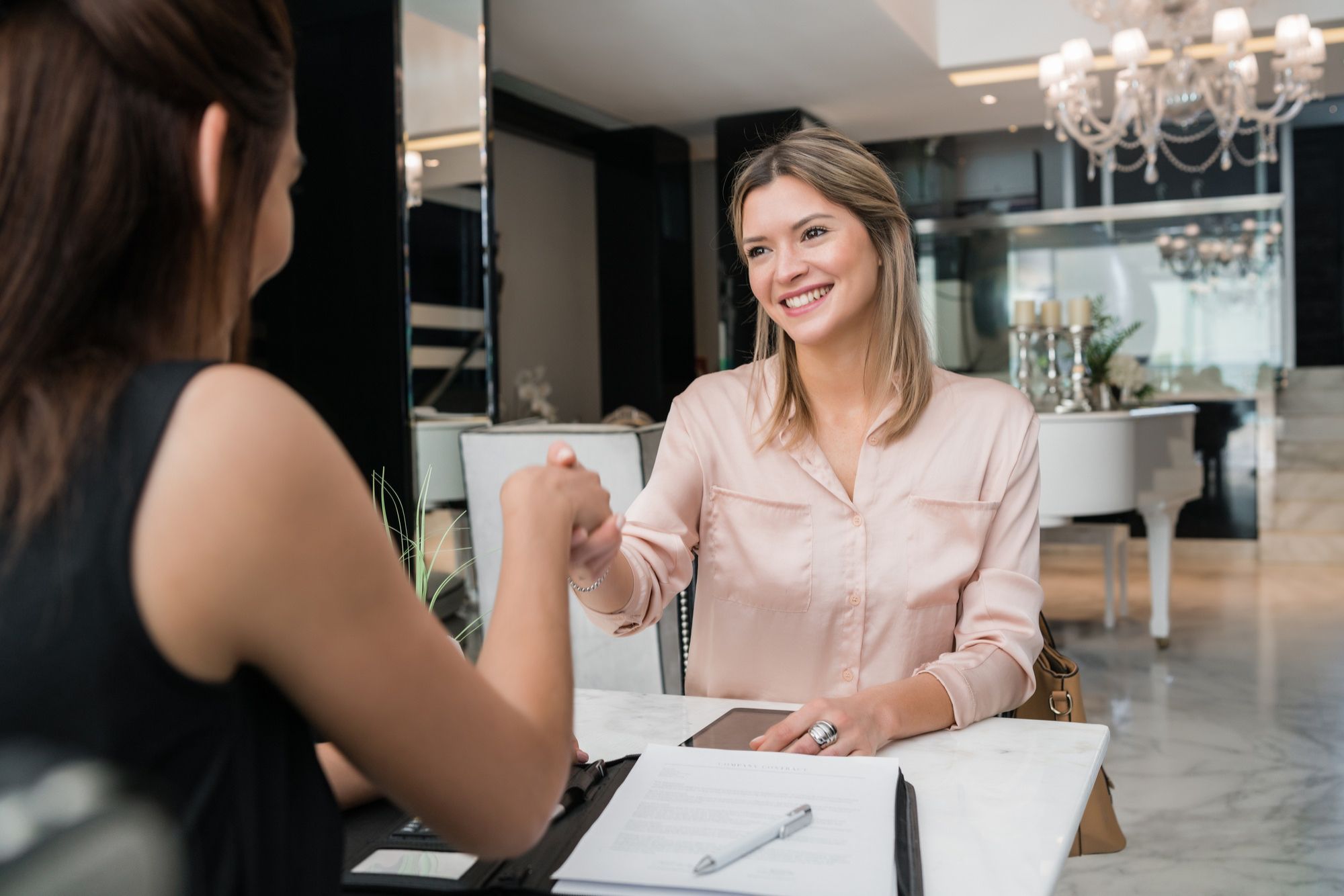 portrait-two-young-businesswomen-having-meeting-shaking-hands-hotel-lobby-business-travel-concept