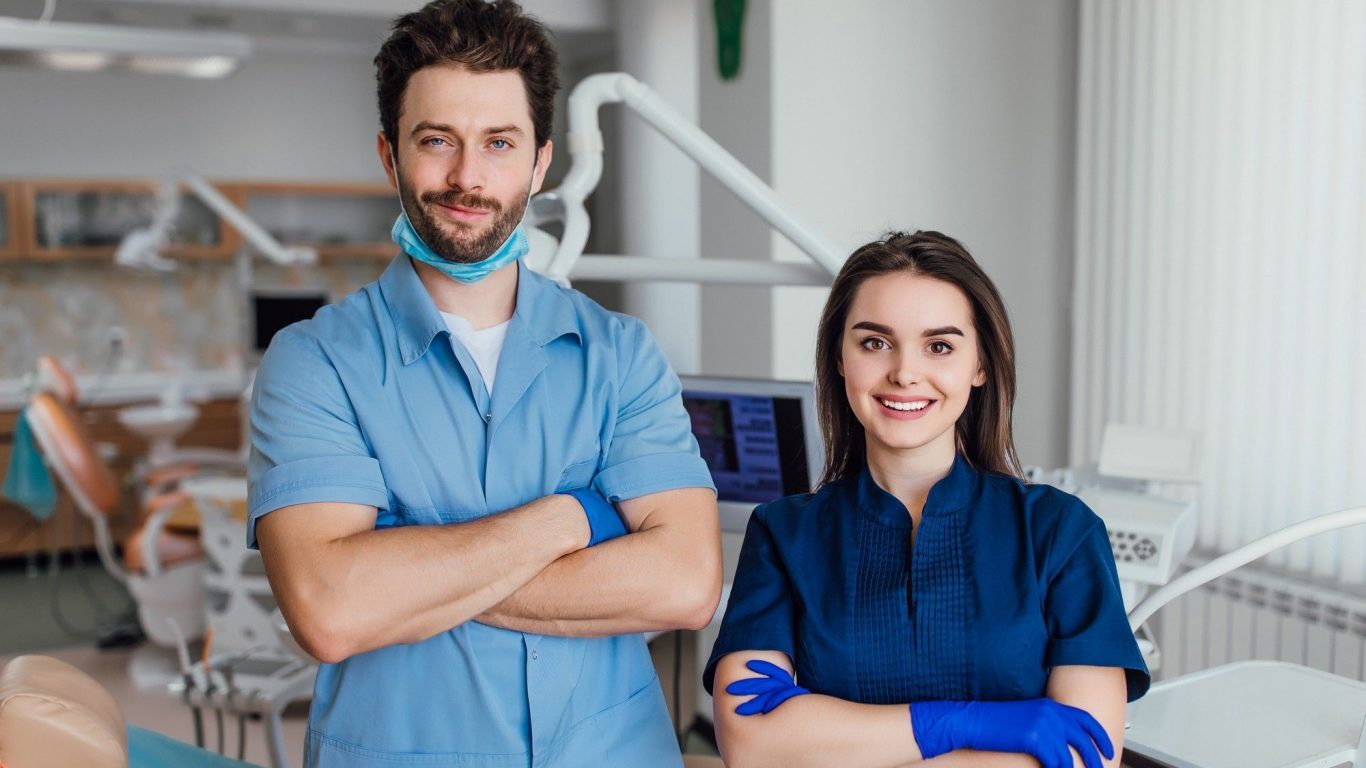 portrait-smiling-dentist-standing-with-arms-crossed-with-her-colleague